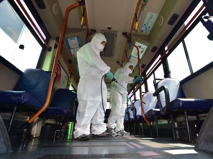 South Korean health workers wearing protective gear sanitize a public bus at a transport company in Seoul on June 15, 2015. South Korea reported on June 15, two more deaths and five new cases in the growing outbreak of MERS which has placed more than 5,200 people under quarantine and sparked widespread alarm. AFP PHOTO / JUNG YEON-JE