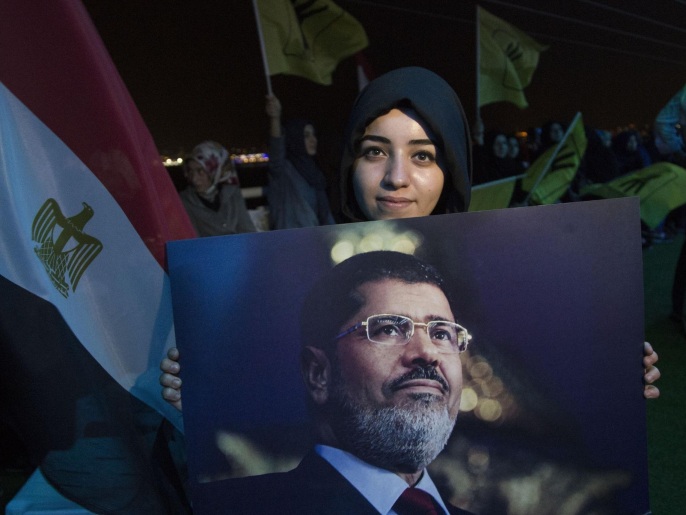  إحدى المتظاهرات تحمل صورة الرئيس المعزول مرسي (غيتي)