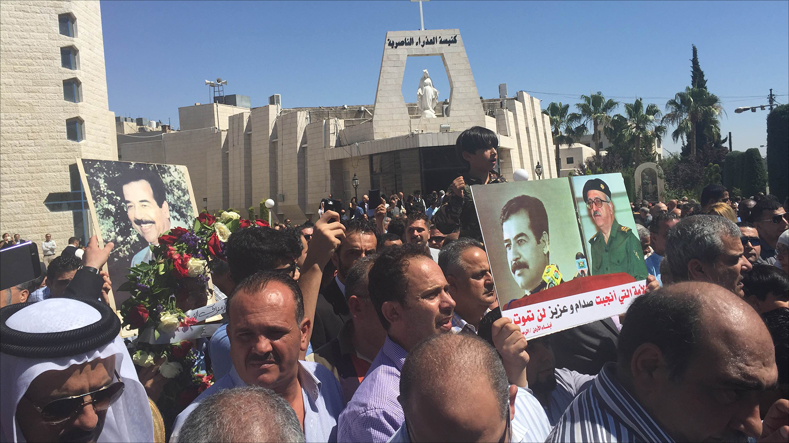 بعض المشاركين في الجنازة التي أُقيمت في عمان رفعوا صورا لصدام حسين وطارق عزيز (الجزيرة نت)