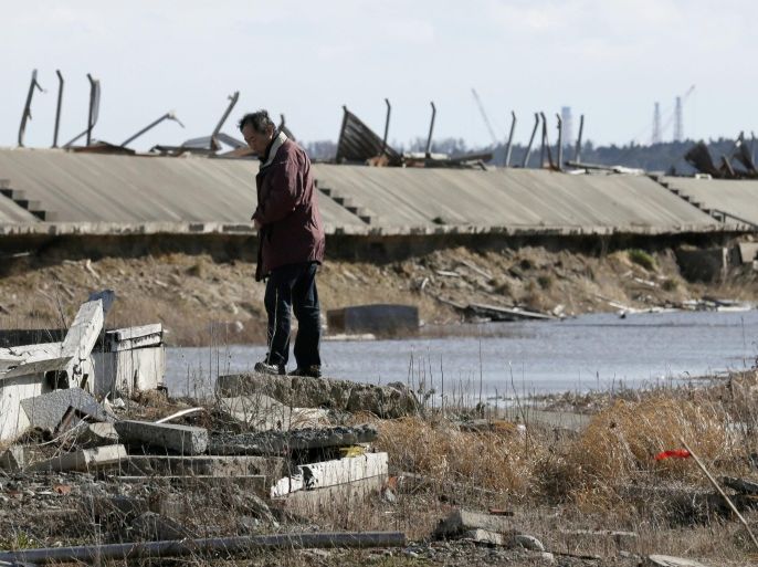 A man is standing on basement of a house destroyed by tsunami at Ukedo in Namie, about five km north of tsunami-crippled Tokyo Electric Company's Fukushima Daiichi Nuclear Power Plant (seen in right rear), Fukushima Prefecture, northern Japan, 10 March 2015, the eve of fourth anniversary of the March 11 earthquake and tsunami in 2011. Namie town, close to Fukushima Daiichi Nuclear Power Plant, had the largest number of such deaths at 359. The plant suffered a triple meltdown caused by the March 11, 2011 earthquake and tsunami that left about 18,500 dead.