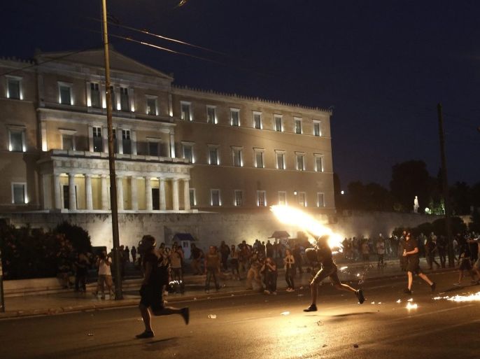 Protesters throw petrol bombs to policemen in front of the parliament during a demonstration against the prior actions expected to be voted by lawmakers, in Athens, Greece, 15 July 2015. A debate on reforms that are key to a preliminary agreement with creditors to keep Greece out of bankruptcy takes place in the country's legislature, but fissures were already beginning to show among the ruling SYRIZA party.