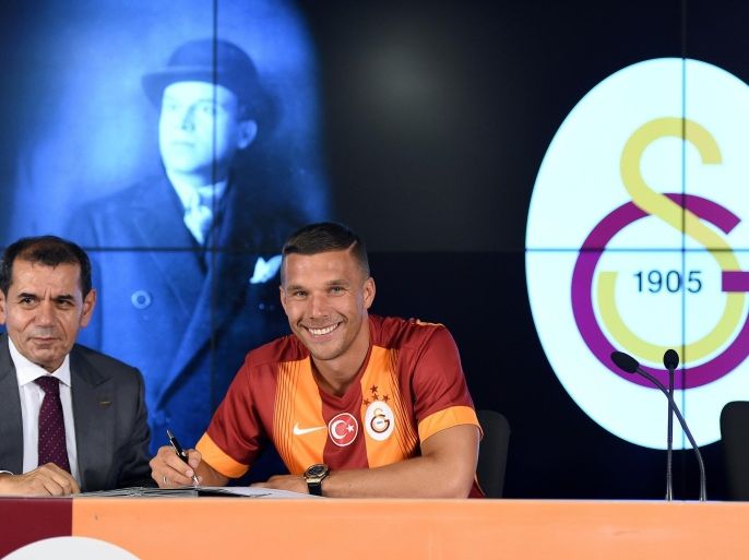 Galatasaray's new German forward Lukas Podolski (R) signs his new contract next to Galatasaray's president Dursun Ozbek (L) during a signing cerenomy on July 4, 2015 at the TT Arena stadium in Istanbul. Lukas Podolski signed a three year contract with Galatasary. AFP PHTO/ OZAN KOSE