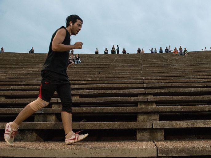PHNOM PENH, CAMBODIA - MAY 24: A jogger runs laps around Phnom Penh's Olympic Stadium on May 24, 2014 in Phnom Penh, Cambodia. The stadium was designed by Vann Molyvann, one of Cambodia's most prominent architects. Cambodians remain statistically some of the thinnest people in the world while in other Asian nations, such as Malaysia, obesity has become a major issue. Though economic hardships and strenuous labour are largely responsible for the slimness of Cambodians rural citizens, for residents of the capital - who often have sedentary jobs and access to high-fat, fast food diets - public exercise facilities keep the public health in check. Group aerobic dance classes are held twice daily in the Olympic Stadium, and along the bustling riverside district, with both locations also offering space for jogging, callisthenics, and weight training.