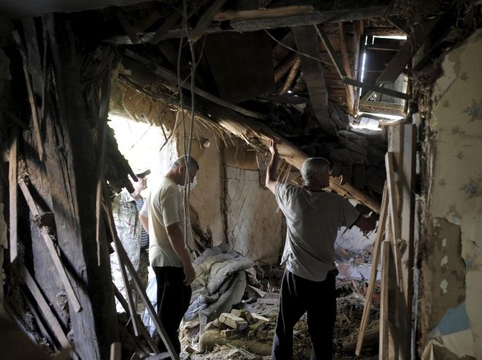 Local residents remove debris inside a damaged building, which according to locals was caused by recent shelling, in Avdiivka in Donetsk region, Ukraine, July 18, 2015. REUTERS/Maksim Levin