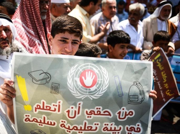 طفل يحمل لافتة أثناء الوقفة الاحتجاجية أمام مقر الأونروا في غزة وكالة الأناضول
