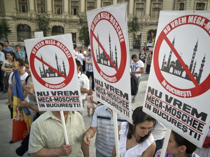 People hold posters that read "We don't want a mega-mosque in Bucharest" during a protest against the planned construction of a mosque in Bucharest, Romania, Monday, July 20, 2015. Protesters, many associated with a right wing organization, called on the government to revoke the decision to give a plot of land in the northern part of the Romanian capital to an organization representing the Muslim community in Romania where a mosque will be built with Turkish government funding. (AP Photo/Vadim Ghirda)
