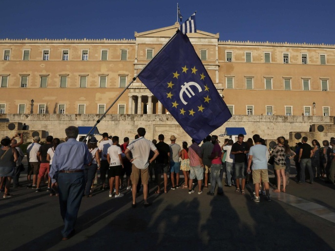 ‪يوناني يحمل علم الاتحاد الأوروبي في مظاهرة أمام برلمان بلاده تطالب ببقاء أثينا بمنطقة اليورو‬ (رويترز)