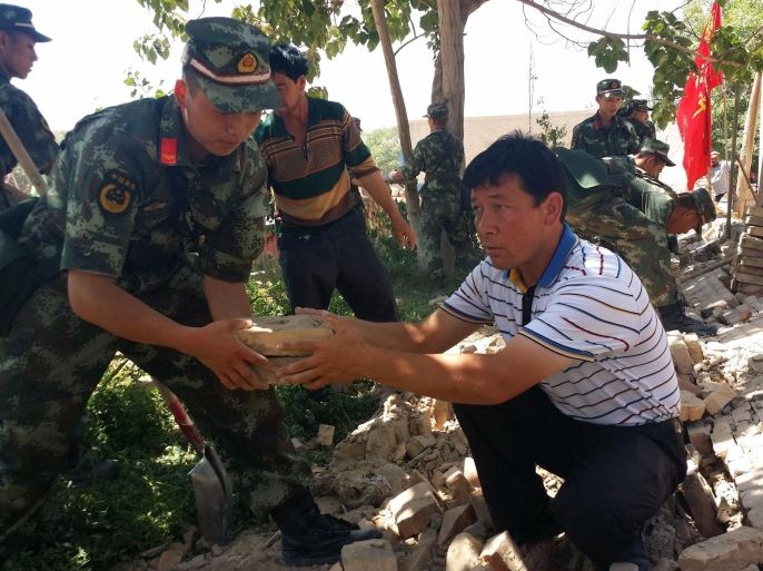 Rescuers help villagers dismantle a damaged wall after an earthquake hit the area in Pishan county in Hetian, in China's northeast Xinjiang region on July 3, 2015. A shallow 6.4-magnitude earthquake struck China's far western region of Xinjiang, the US Geological Survey said, with at least six people killed according to Chinese officials. CHINA OUT AFP PHOTO