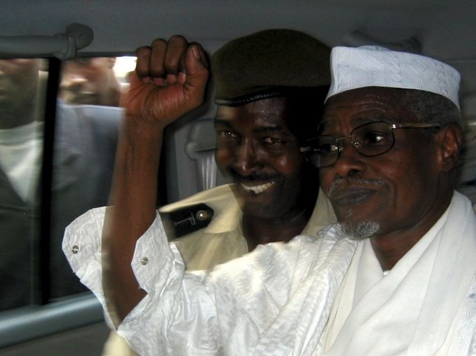 Former Chad President Hissene Habre (R) raises his fist in the air as he leaves a court in Dakar escorted by a Senegalese policeman in this November 25, 2005 file photo. With many Africans denouncing the International Criminal Court as 'white man's justice', the trial of Habre, Chad's former dictator, in Senegal on charges of crimes against humanity offers the continent a chance to show it can hold its leaders to account. REUTERS/Aliou Mbaye/Files