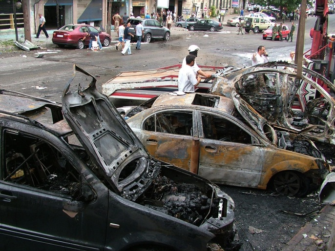 ‪(أسوشيتد برس)‬ سيارات محترقة جراء سقوط صواريخ أمام دار الفتوى باللاذقية قبل أربعة أيام