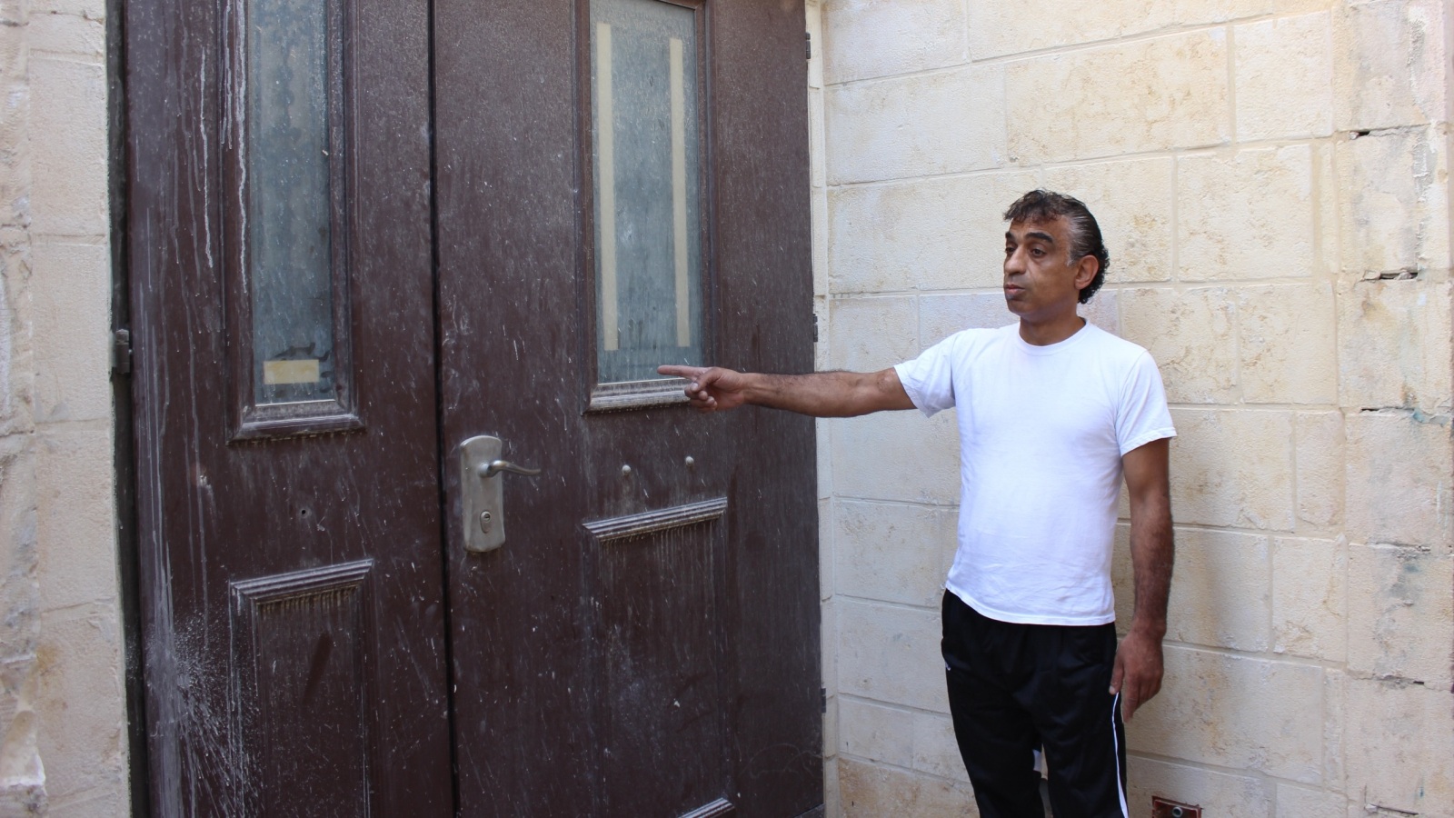 ‪‬ خميس عوض صاحب المنزل يشير إلى باب الكنيس الذي تم فتحه من مدخل منزله(الجزيرة)