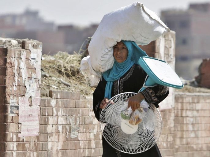 An Egyptian farmer carries an electric fan as she walks through a Cairo street , Egypt, Tuesday, Aug. 11, 2015. Egyptian health authorities say at least 40 people have died in the last two days amid a scorching heatwave hitting the country. (AP Photo/Amr Nabil)