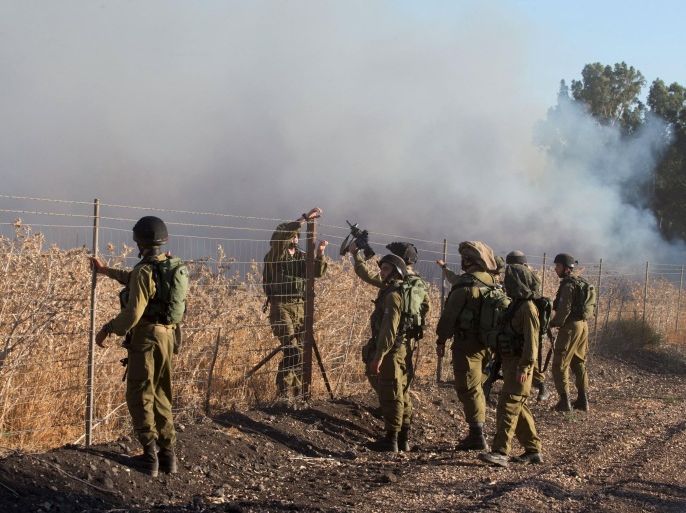 Israeli soldiers stand next to smoke from a fire caused by a rocket attack in northern Israel, near the Lebanese border, August 20, 2015. Rockets that struck an northern Israeli village near the Lebanese border on Thursday, causing no casualties, were launched from the Syrian Golan Heights, the Israeli army said. REUTERS/JINIPIX ISRAEL OUT