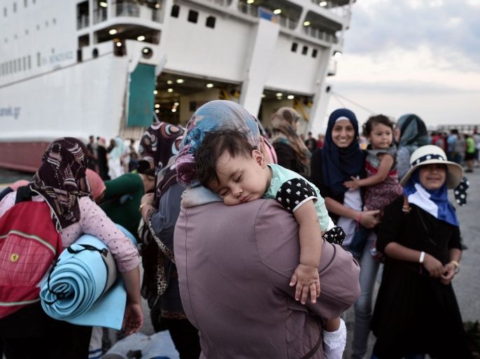 LOU3429 - Piraeus, -, GREECE : A woman carries her child as migrants disembark at the port of Piraeus from the Greek government-chartered Eleftherios Venizelos ferry on August 21, 2015. A Greek government-chartered ferry transported another 2,000 mainly Syrian migrants to the Greek mainland from the island of Lesbos, as islands struggling with an influx of migrants warned that the crisis is endangering public health. AFP PHOTO /LOUISA GOULIAMAKI