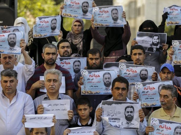 Protesters hold a picture of Palestinian prisoner Mohammed Allaan, with slogan reading 'Mohammed Allaan in hunger strike his Life under threatening' and 'Allaan, is jailed in Israel' during a solidarity protest at in the West Bank city of Hebron , 15 August 2015, Allaan, a member of the Islamic Jihad militant movement, jailed for the third time as administrative prisoner, has been on hunger strike for 61 days.