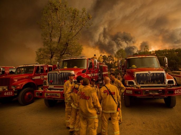 Firefighters confer as the Rocky fire burns near Clearlake, California, USA, 01 August 2015. The fire, one of dozens raging in drought parched Northern California, has destroyed 24 residences and scorched 25,750 acres according to Cal Fire. Thousands of firefighters battle blazes in northern California, where record heat and dry conditions were complicating efforts to extinguish them. More than 20 large wildfires are burning in the state, many caused by lightning strikes. Governor Jerry Brown declared a state of emergency, saying severe drought and extreme weather have turned much of the state into a tinderbox.