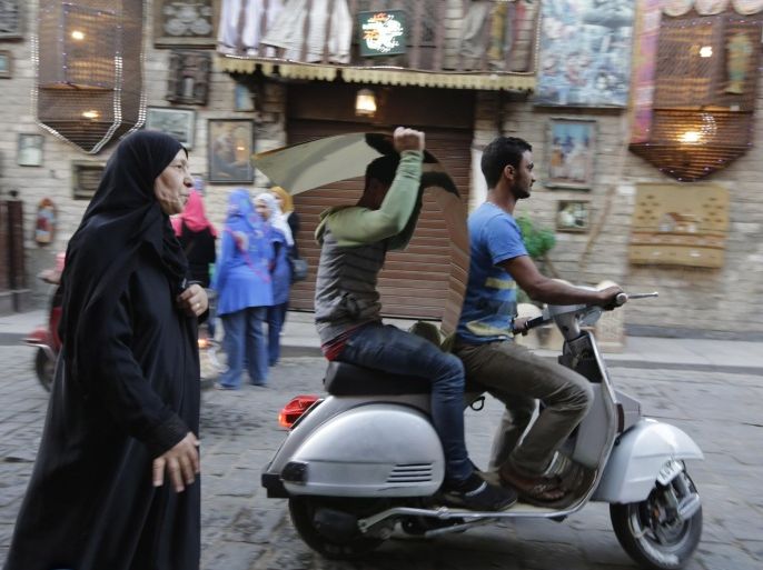 In this Monday, May 18, 2015 photo, An Egyptian worker carries a metal plate as he rides a motor bike at el-Moez Street in historical Fatimid Cairo. Egypt is making its most ambitious push to lure foreign and private investors, hoping to propel growth and provide employment after four years of turmoil that have brutalized the economy since the 2011 uprising that ousted autocrat Hosni Mubarak. (AP Photo/Amr Nabil)