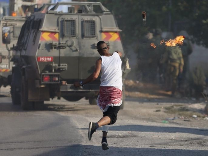 A Palestinian protester throws a molotov cocktail towards Israeli soldiers during clashes following the funeral of Palestinian youth Laith al-Khaldi, in Jalazoun refugee camp near the West Bank city of Ramallah August 1, 2015. Al-Khaldi died on Saturday at a West Bank hospital following a clash with Israeli troops near Ramallah, Palestinian hospital officials said. The confrontation was one of three in a matter of hours in which Palestinians died from Israeli-Palestinian violence on one of the most tense days in the occupied West Bank and the Gaza Strip in recent months. Israeli soldiers fired at the Palestinian after he threw a fire-bomb at them, the military said. REUTERS/Mohamad Torokman