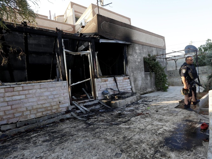‪‬ جندي إسرائيلي يتفقد منزل العائلة الفلسطينية بعد إحراقه على يد مستوطنين(الأوروبية)