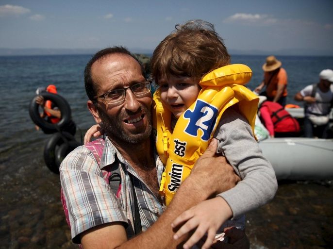Syrian refugee Mustafa Mohammad embraces a boy after arriving on a dinghy at the Greek island of Lesbos August 6, 2015. The U.N refugee agency, UNHCR, estimates that Greece has received more than 107,000 refugees and migrants this year, more than double its 43,500 intake of 2014. REUTERS/Yiannis Kourtoglou
