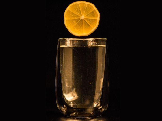 Sliced Lemon Over Glass Of Water Against Black Background