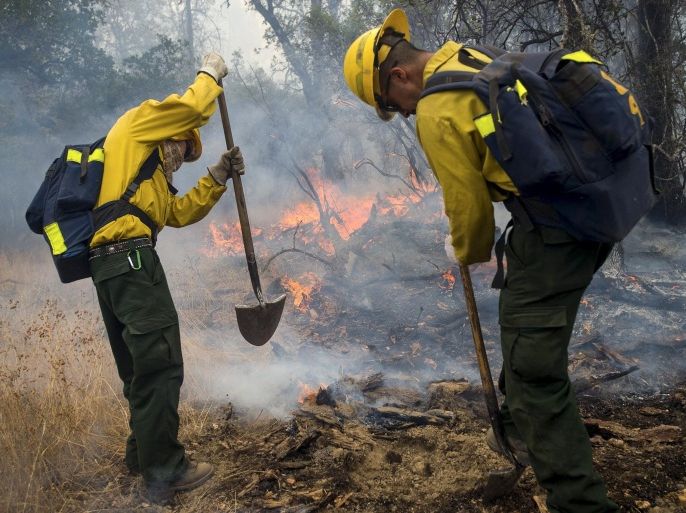Firefighters throw dirt on a hot spot while battling the Valley Fire near Middleton, California September 14, 2015. The Northern California wildfire ranked as the most destructive to hit the drought-stricken U.S. West this year has killed one woman and burned some 400 homes to the ground, fire officials said on Monday, and they expect the property toll to climb. The so-called Valley Fire erupted on Saturday and spread quickly to a cluster of small communities in the hills and valleys north of Napa County's wine-producing region, forcing the evacuation of thousands of residents. REUTERS/Noah Berger