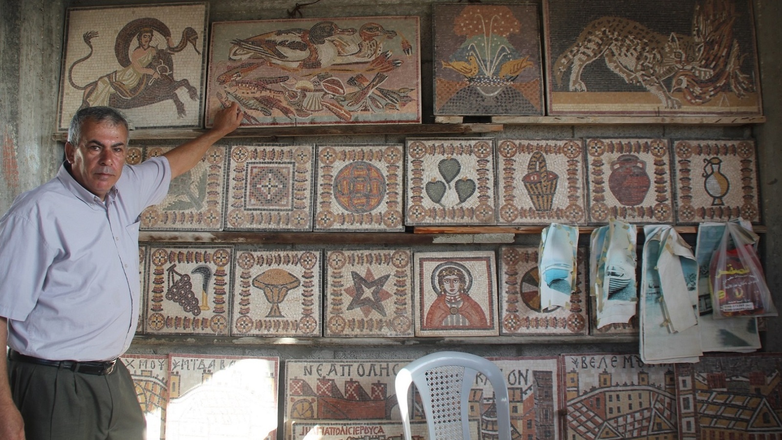 ‪نافذ عابد يقف إلى جانب عدد من لوحات الفسيفساء المقلدة التي أبدعها بيده‬ (الجزيرة)