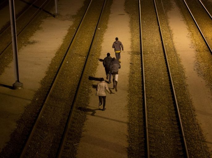 FILE - In this Tuesday, Aug. 4, 2015 file photo, migrants run a long the train track after crossing a fence as they attempt to access the Channel Tunnel in Calais, northern France. A gallery of images recounting the lives of some of the estimated 3,000 migrants who have gathered in the northern French port city of Calais, most feeding on the hope of sneaking across the English Channel to settle in Britain. (AP Photo/Emilio Morenatti, File)