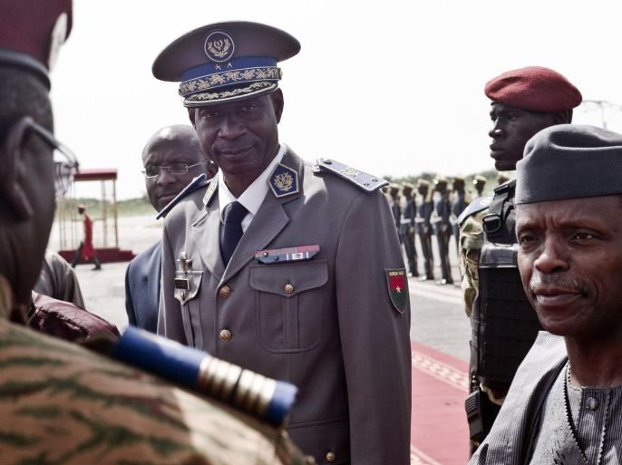 Burkina Faso coup leader Gen. Gilbert Diendere, center, greets people at the airport during the arrival of Niger's President Mahamadou Issoufou for talks in Ouagadougou, Burkina Faso, Wednesday, Sept. 23, 2015. Burkina Faso's interim president declared Wednesday he is once again in charge of the country a week after a military general and his supporters overthrew him and his transitional government. Interim President Michel Kafando had been arrested by members of the presidential guard a week ago, and later sought refuge at the residence of the French ambassador. (AP Photo)