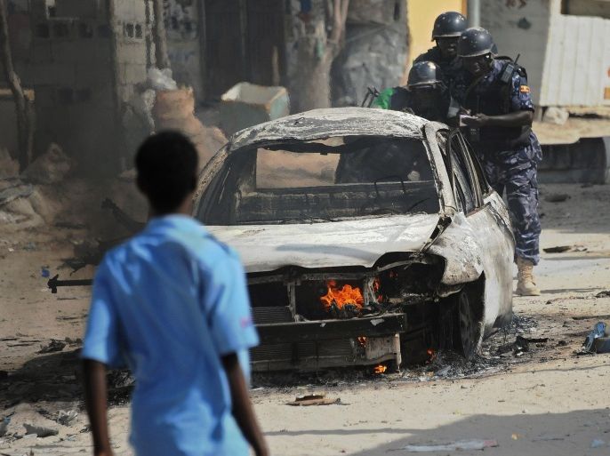 African Union Mission in Somalia (AMISOM) soldiers record details at the wreckage of a car bomb in the Wardhigley District south of Mogadishu on February 27, 2015. The bomb killed one person and injured another. AFP PHOTO / Mohamed Abdiwahab