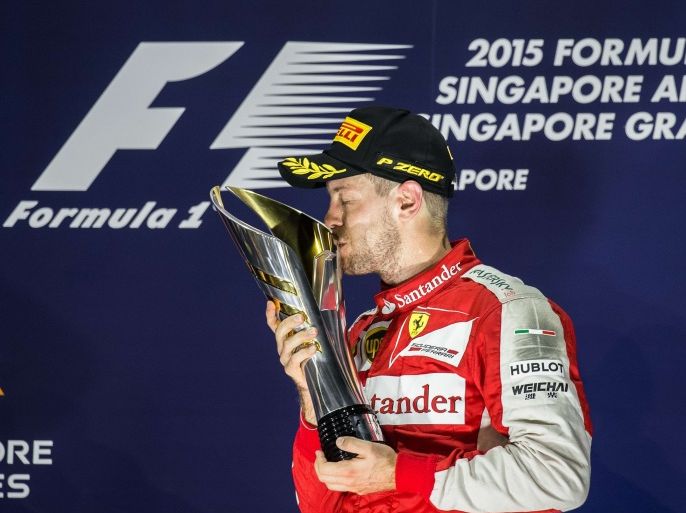 PL20 - Singapore, -, SINGAPORE : Ferrari's German driver Sebastian Vettel kisses the trophy on the podium after winning the Formula One Singapore Grand Prix in Singapore on September 20, 2015. AFP PHOTO / Philippe Lopez