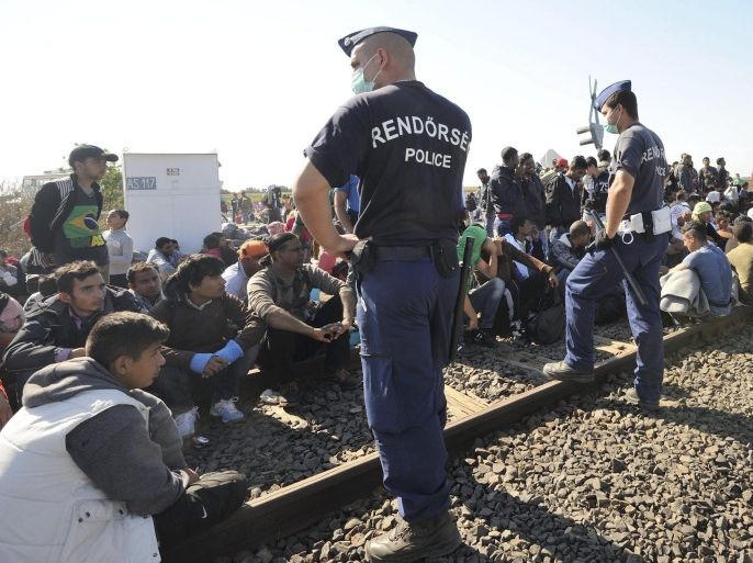 Migrants who arrived from Serbia are guarded by Hungarian police officers at a collection point before a group leaves the point arbitrarily near the border village of Roszke, 180 kms southeast of Budapest, Hungary, 09 September 2015. Later group of 200-250 migrants were rounded by police on the motorway to Budapest and the migrants agreed to be transported to a registration centre. EPA/Zoltan Gergely Kelemen HUNGARY OUT