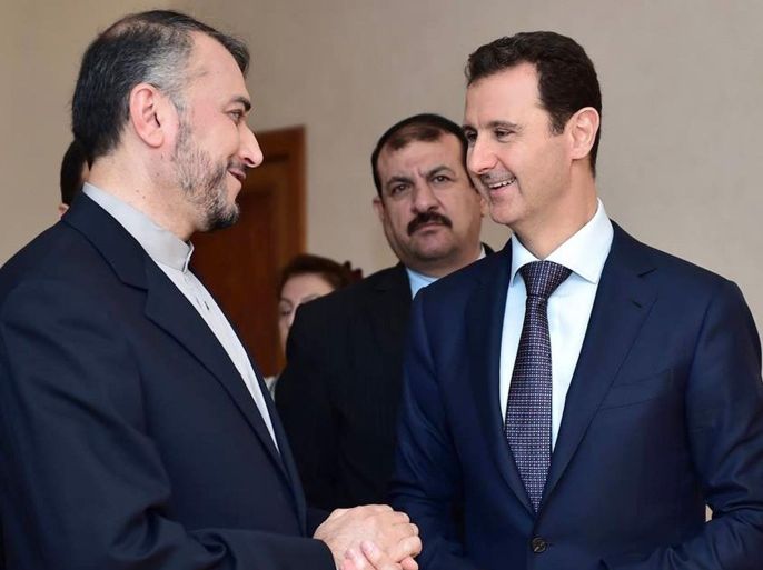 In this photo released on the official Facebook page of the Syrian Presidency, Syrian President Bashar Assad, right, speaks with Iran's Deputy Foreign Minister Hossein Amir Abdollahian, left, in Damascus, Syria, Thursday, Sept. 3, 2015. Abdollahian says Syrian President Bashar Assad has a “pivotal and central” role to play in the war on terrorism and is an important part of any solution for the war-torn country. (Syrian Presidency via Facebook)