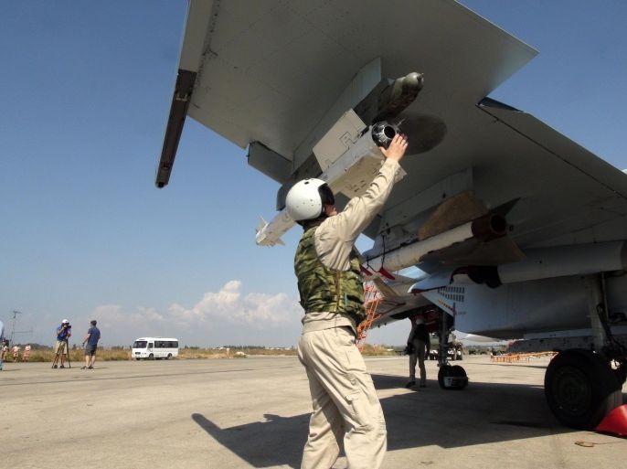 In this photo taken on Monday, Oct. 5, 2015, a Russian pilot fixes an air-to-air missile at his Su-30 jet fighter before a take off at Hmeimim airbase in Syria. NATO also strongly criticized the Russian air campaign in Syria that began Wednesday. (AP Photo/Dmitry Steshin, Komsomolskaya Pravda, Photo via AP)