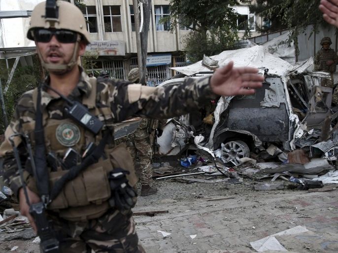 Members of Afghan security forces keep watch in front of a damaged car that belongs to foreigners after a bomb blast in Kabul, Afghanistan August 22, 2015. A car bomb outside a Kabul hospital killed at least 10 people and caused widespread casualties among Afghan civilians, although it appeared to have targeted a vehicle carrying foreign citizens, witnesses and security sources said. REUTERS/Ahmad Masood