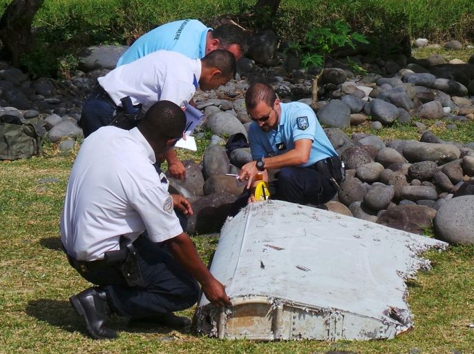 File picture shows French gendarmes and police inspecting a large piece of plane debris which was found on the beach in Saint-Andre, on the French Indian Ocean island of La Reunion, July 29, 2015. French prosecutor announced on Thursday that we can say with certainty that the wing part found on Saint-Andre beach was from missing Malaysia Airlines Flight MH370. REUTERS/Zinfos974/Prisca Bigot/Files TPX IMAGES OF THE DAY