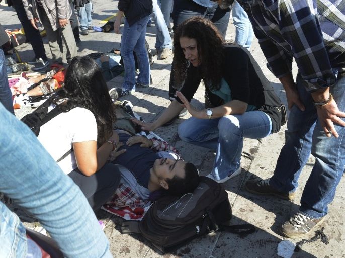 People tend to a victim at the site of an explosion in Ankara, Turkey, Saturday, Oct. 10, 2015. The two bomb explosions targeting a peace rally in the capital Ankara has killed dozens of people and injured scores of others. The explosions occurred minutes apart near Ankara's main train station as people were gathering for the rally, organized by the country's public sector workers' trade union and other civic society groups. The rally aimed to call for an end to the renewed violence between Kurdish rebels and Turkish security forces. (AP Photo)
