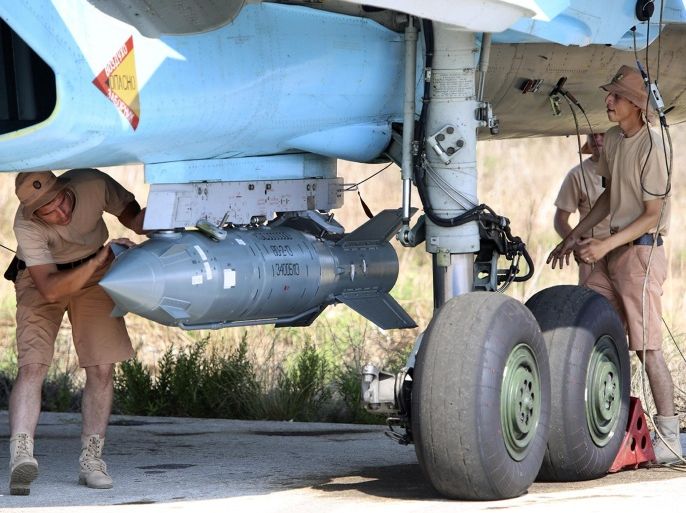 In this photo taken on Saturday, Oct. 3, 2015, Russian military support crew attach a satellite guided bomb to SU-34 jet fighter at Hmeimim airbase in Syria. Russia has insisted that the airstrikes that began Wednesday are targeting the Islamic State group and al-Qaida's Syrian affiliates, but at least some of the strikes appear to have hit Western-backed rebel factions. (AP Photo/Alexander Kots, Komsomolskaya Pravda, Photo via AP)