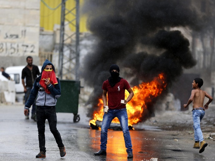 فلسطينيون يرشقون الحجارة أثناء اشتباكات مع قوات الاحتلال بالخليل أمس (الأوروبية)