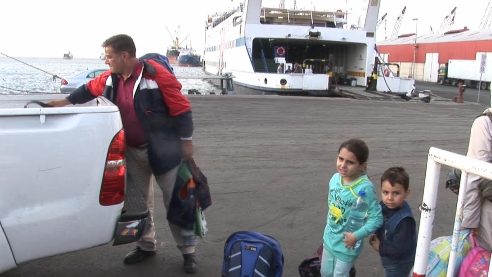 لاجئون سوريون يتوجهون نحو إحدى السفن المتوجهة إلى تركيا (الجزيرة)