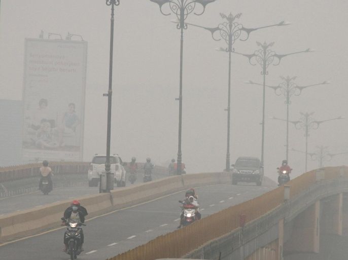 Cars and motorcycles are seen on a bridge as haze shrouds Pekanbaru, in Indonesia's Riau province, September 30, 2015 in this picture taken by Antara Foto. Indonesia has sent nearly 21,000 personnel to fight forest fires raging in its northern islands, the disaster management agency said on Tuesday, but smoke cloaks much of the region with pollution readings in the "very unhealthy" region in neighboring Singapore. REUTERS/Rony Muharrman/Antara Foto ATTENTION EDITORS - THIS IMAGE WAS PROVIDED BY A THIRD PARTY. IT IS DISTRIBUTED EXACTLY AS RECEIVED BY REUTERS, AS A SERVICE TO CLIENTS. FOR EDITORIAL USE ONLY. NOT FOR SALE FOR MARKETING OR ADVERTISING CAMPAIGNS. MANDATORY CREDIT. INDONESIA OUT. NO COMMERCIAL OR EDITORIAL SALES IN INDONESIA.