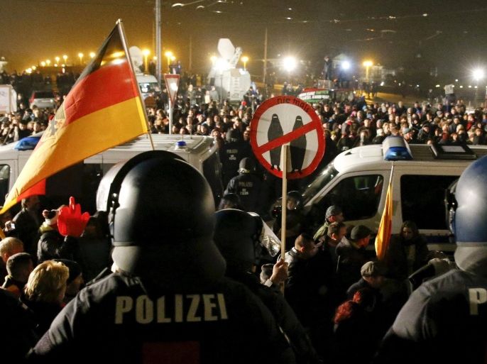 People attending an anti-immigration demonstration organised by rightwing movement Patriotic Europeans Against the Islamisation of the West (PEGIDA) walk past opponents of PEGIDA behind police cars, in Dresden, Germany October 19, 2015. PEGIDA held a rally on Monday to mark the one-year anniversary of the group's formation. REUTERS/Fabrizio Bensch