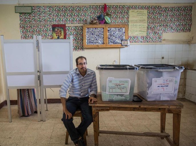 An election monitor sits next to ballot boxes at a polling station during the final day of the first round of parliamentary election, in Fayoum, Egypt, Monday, Oct. 19, 2015. Egyptian authorities have given government workers a half-day off Monday in an attempt to bolster low turnout in the country’s parliamentary election. The government has not released turnout figures for voting on Sunday. (AP Photo/Eman Helal)
