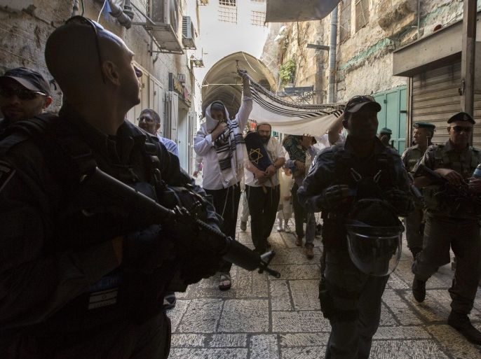 An Israeli Border Policeman looks towards the roof tops in Jerusalem's Old City as a security detail escort Jewish settlers who live in the Moslem Quarter towards the Western Wall area on 05 October 2015. The Jews carry torah scrolls and are singing and dancing under a religious p prayer shawl as they celebrate Simchat Torah, a time of rejoicing marking the completion of the cycle of reading the Torah. Israel has increased security due to the recent wave of increased attacks and closed the Old City to Moslems who are not residents of the Old City, something they have never before done.