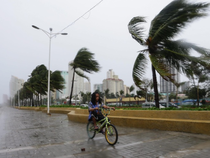فلبيني يستقل دراجة بخليج مانيلا اليوم في الوقت الذي وصل فيه إعصار كوبو الأجزاء الشمالية من البلاد (الأوروبية)