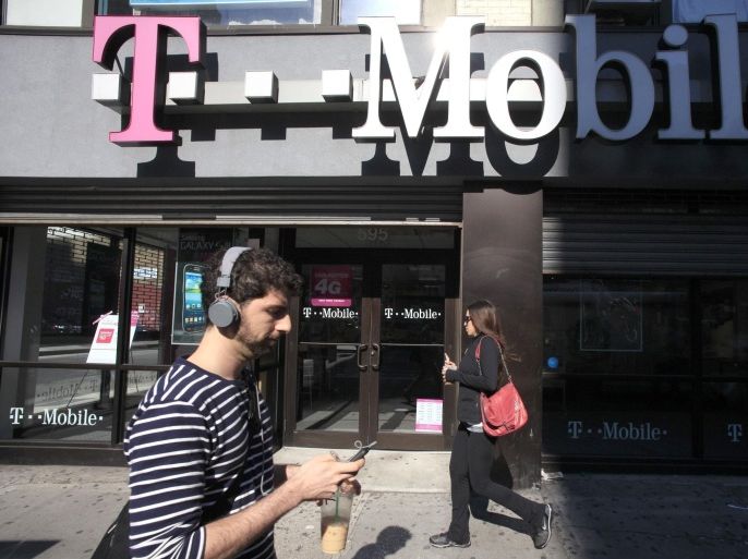 FILE - In this Sept. 12, 2012 file photo, a man uses a cellphone as he passes a T-Mobile store in New York. Credit reporting agency Experian on Thursday, Oct. 1, 2015 said that hackers accessed the social security numbers, birthdates and other personal information belonging to about 15 million T-Mobile wireless customers. T-Mobile uses Experian to check the credit of its customers. (AP Photo/Mark Lennihan, File)