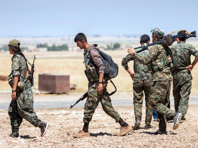 Kurdish People's Protection Units (YPG) fighters walk with their weapons at the eastern entrances to the town of Tal Abyad in the northern Raqqa countryside, Syria, June 14, 2015, after taking control of nearby Suluk town from Islamic State fighters. The YPG, working with the U.S.-led alliance and small Syrian rebel groups, has pushed into Islamic State's Syrian stronghold of Raqqa province, threatening one of its supply lines to the jihadists' de facto capital, Raqqa city. REUTERS/Rodi Said