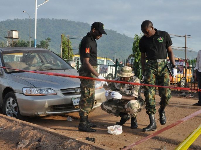 Soldiers gather at the site of a bomb explosion in Abuja, Nigeria, Saturday, Oct. 3, 2015. Multiple bombs detonated in two locations killing at least 15 people, the National Emergency Management Agency said Saturday, although no group has claimed responsibility the attack has attributes of others by Boko Haram, the home-grown Islamic extremist group.(AP Photo/Gbenga Olamikan)