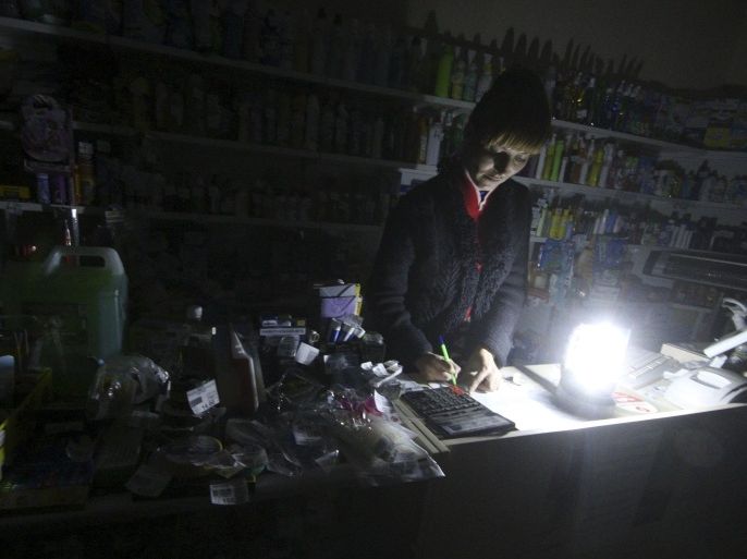 An employee works at an appliance shop lit with candles due to a power cut, in Simferopol, Crimea, November 22, 2015. REUTERS/Pavel Rebrov