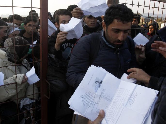 People hand in their documents for identification at the entrance of the transit center for refugees near the southern Macedonian town of Gevgelija, after crossing the border from Greece, Saturday, Nov. 14, 2015. Hundreds of thousands of migrants and refugees have passed the last few months through Macedonia as a part of the Balkan route, on their way to more prosperous European Union countries. (AP Photo/Boris Grdanoski)